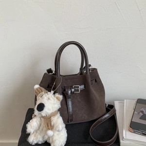 Detail of dark brown woven texture bucket bag with a cute white bear charm accessory