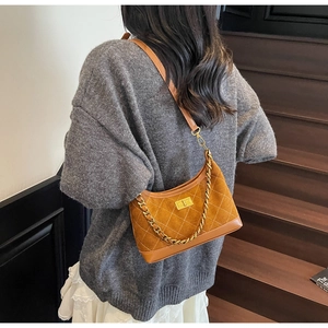 Detail of a brown suede quilted shoulder bag with gold chain strap and metal lock buckle