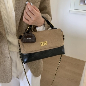Close-up of contrast stitch quilted handbag with gold clasp and chain strap