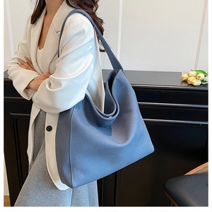 Close-up of fog blue large tote bag with wide shoulder strap on a model in white blazer