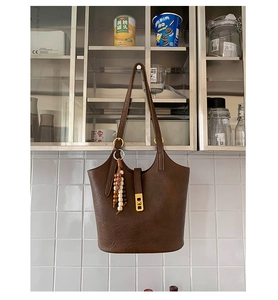 Close-up of brown vintage bucket bag with gold hardware and decorative wooden beads detail