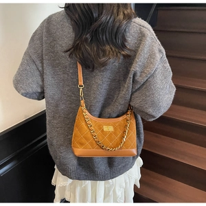 Detailed close-up of quilted suede shoulder bag with gold chain and turn-lock closure