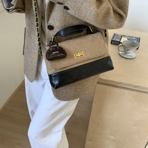 Detailed shot of textured stitching, golden turn-lock, and mini charm on a crossbody bag