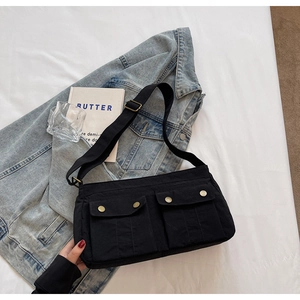 Detail of black canvas shoulder bag with dual front pockets and vintage metal buckles