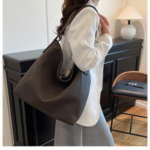 Close-up of a large coffee leather tote bag with soft texture and hobo bucket style