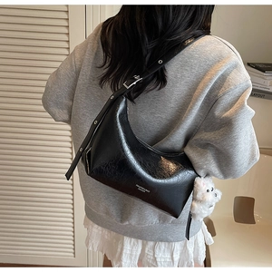 Detail of black crescent shoulder bag with pleated leather and white bear charm decoration