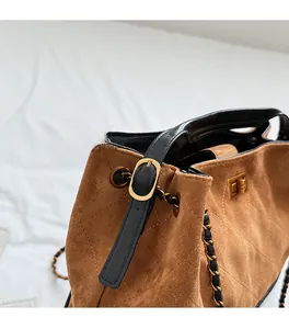 Close-up of brown suede tote with diamond stitching and golden turn-lock closure