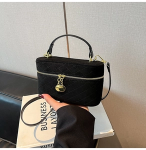 Detailed close-up of a black quilted velvet box bag featuring gold hardware and a handle