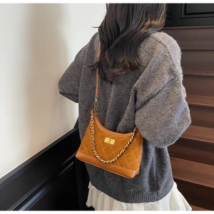 Detail of brown suede crossbody bag with diamond quilting and gold chain strap