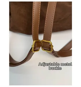 Detailed macro view of gold-tone hardware buckle and adjustable strap on brown PU bag