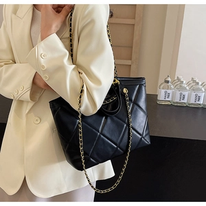Close-up of black quilted tote bag with signature gold chain strap on shoulder