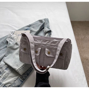 Detail of light grey nylon shoulder bag featuring textured fabric and front utility pockets
