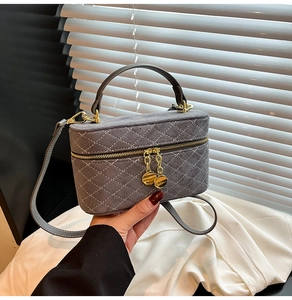 Detail of grey quilted suede box bag with dual metal zipper pendants and slim shoulder strap