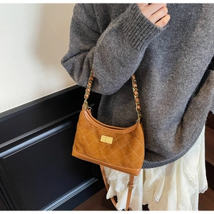 Detailed macro view of caramel suede texture and golden chain strap on shoulder bag