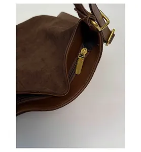 Detail of the golden zipper and dark brown suede texture on the retro bucket bag