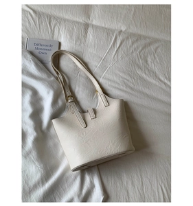 Close-up of beige bucket bag with adjustable gold buckle and pebble leather texture