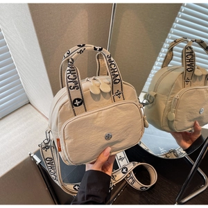 Details der beigen Nylon-Umhängetasche mit Blumengurt und Reißverschlussfach