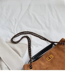 Close-up of brown suede tote bag with diamond quilting and gold chain strap detail