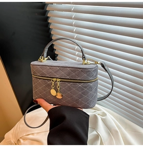 Detail of grey quilted suede box bag with white stitching and gold hardware accents