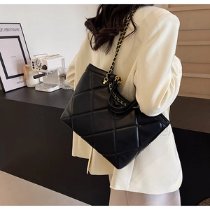 Detail of classic black quilted tote bag with elegant gold-tone chain strap