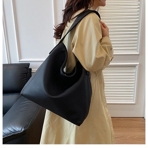 Vista lateral detallada de un bolso tote grande negro vintage llevado por una modelo