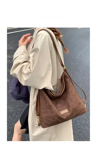Close-up of brown suede hobo tote bag featuring a vintage rectangular fashion label