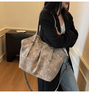 Detail of the vintage gray tote bag showing adjustable metal buckles and leather texture