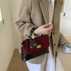 Detail showing burgundy suede and black quilted leather handbag held by a female model