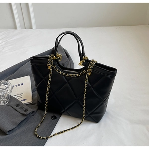 Detailed view of the black quilted tote bag with elegant gold chain shoulder strap