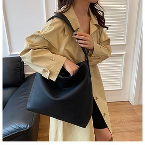Detail view of a black large-capacity leather hobo shoulder bag shown on a model