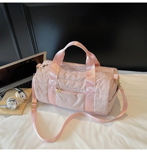 Close-up of pink quilted travel bag with gold hardware and side pocket on desk