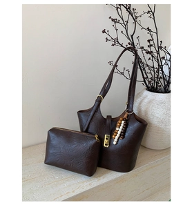 Close-up of vintage brown leather tote bag with wooden bead tassel and metal clasp detail