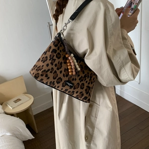 Détail du sac léopard avec bandoulière noire et accessoire pompon en perles de bois