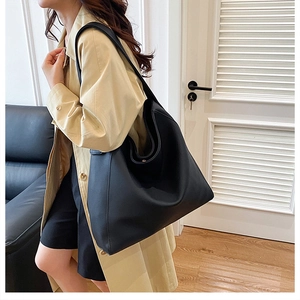 Macro detail of high-quality black leather tote bag showing soft matte texture and draping