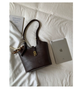 Close-up of vintage dark brown leather bucket bag with gold twist lock and beaded strap