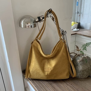 Detail of yellow suede tote bag with FASHION embossed patch and wide shoulder strap