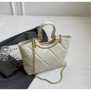 Macro shot of quilted pattern texture and metal chain strap on beige tote bag