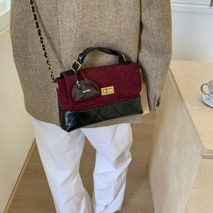 Detail of burgundy suede and black leather chain bag with classic diamond quilting