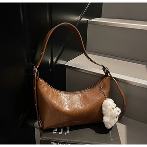 Detail of vintage brown leather shoulder bag with natural texture and cute plush charm
