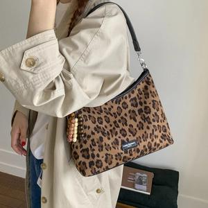 Gros plan du sac léopard avec des pompons en perles et une étiquette de marque chic