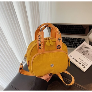 Detail der gelben Nylontasche mit orangefarbenem Stickgurt und Metalllogo