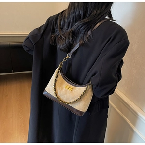 Beige quilted velvet underarm bag with gold chain strap shown on person in home setting