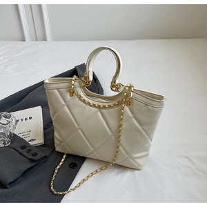 Detail of quilted beige tote bag with gold chain strap and elegant urban styling props