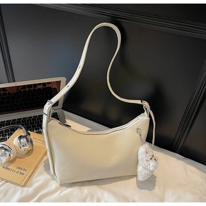 Detailed view of cream dumpling bag with textured leather and cute teddy bear charm