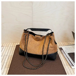 Detail of a brown suede and black quilted leather tote bag with a golden metal lock
