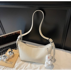 Detail of off-white hobo bag featuring pleated texture, silver hardware and plush pendant