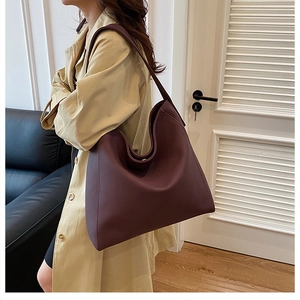 Detail view of large burgundy leather tote bag with wide strap and soft textured finish