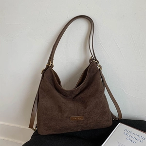 Detail of dark coffee suede tote bag with FASHION label and slim leather straps