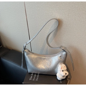 Detail view of silver crescent bag with crinkled texture and plush puppy charm