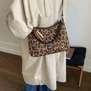 Détail du sac bandoulière léopard vintage avec chaîne en perles et étiquette de marque
